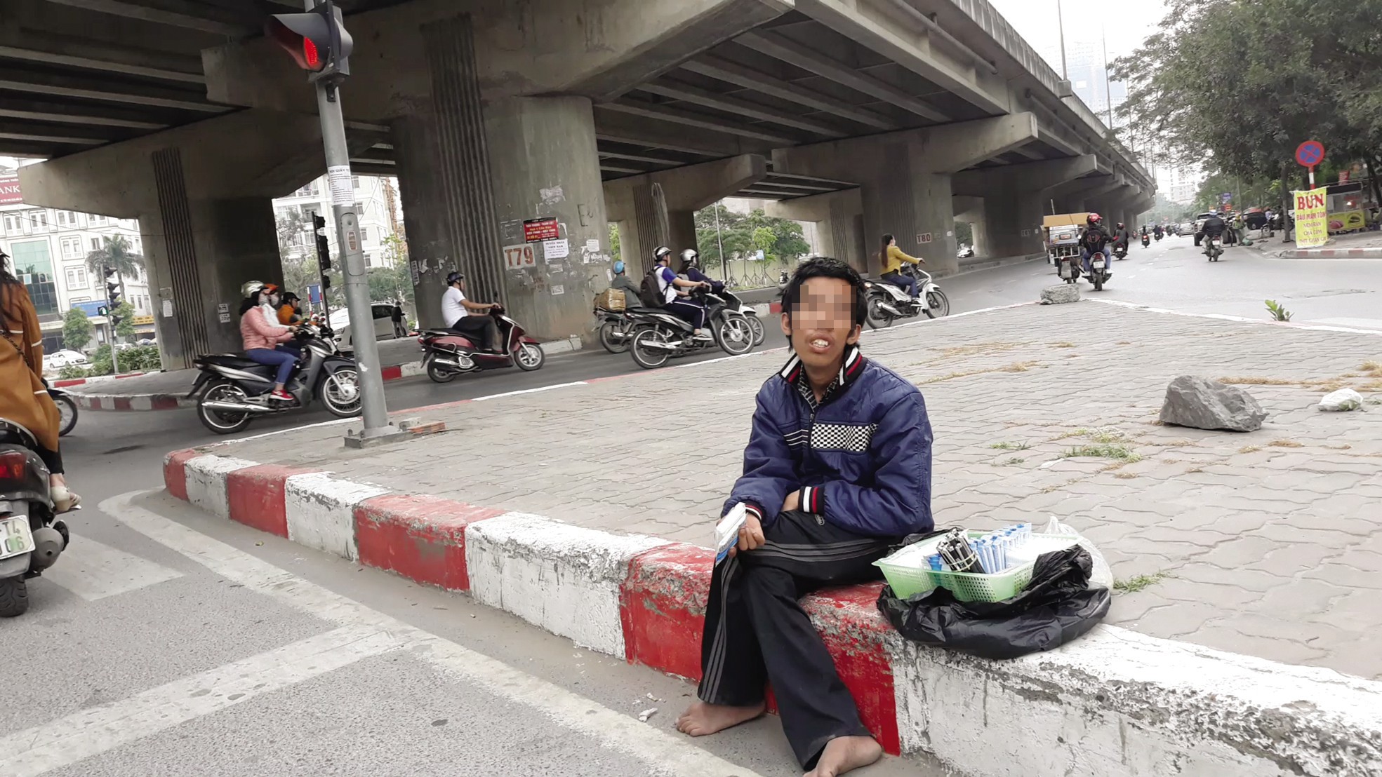 Dù nắng hay mưa anh Nguyên cũng ngồi tại nút giao thông Nguyễn Xiển – Linh Đàm bán hàng rong. Ảnh: PV