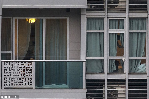 A policeman checks the window (right) in the apartment where the bodies of two women were found