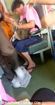 A man known as Jeff braces to be slapped by a monk on a train in Thailand