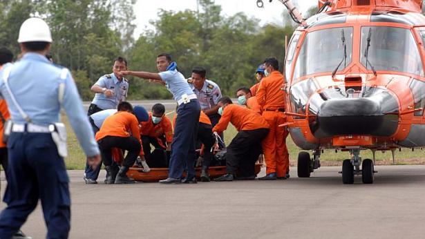 Các thành viên của đội cứu hộ Indonesia đang đưa một thi thể xuống máy bay tại Pangkalan Bun.