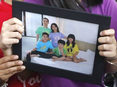 Relatives hold a picture of the Herumanto Tanus family as they wait for news from the missing AirAsia plane
