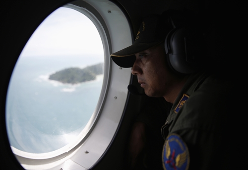 A crew member on an Indonesian Maritime Surveillance looks out the window during a search for AirAsias Flight QZ8501, north of Bangka island December 30, 2014. Indonesian rescuers saw bodies and luggage off the coast of Borneo island on Tuesday and officials said they were