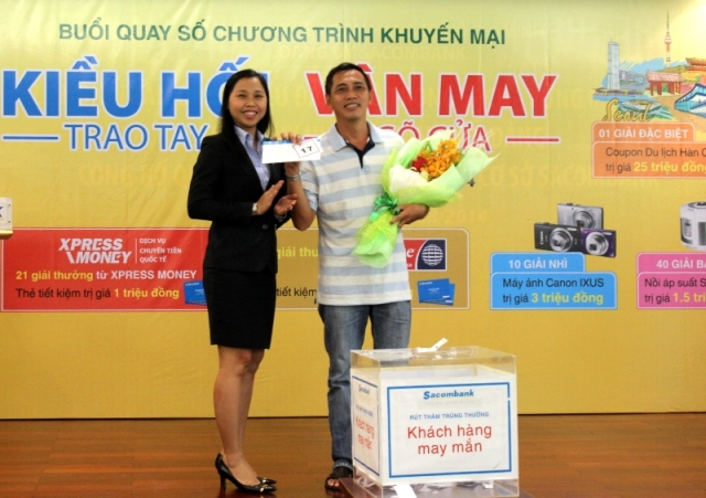Bà Nguyễn Phương Huyền (trái) đại diện Sacombank trao thưởng cho khách hàng may mắn