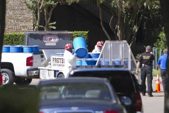 Các nhân viên của đội phản ứng nhanh với dịch Ebola trút thùng nhựa được sử dụng để thu thập các vật dụng trong căn hộ của Amber Vinson ở Texas hôm 15/10. Ảnh Reuters.