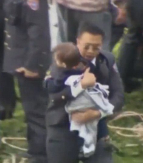 Safe: The toddler and a Taiwanese official rush to safety once they reach dry land, after the little boy is rescued from the plane which crashed into the Keeling River in Taipai, Taiwans capital city