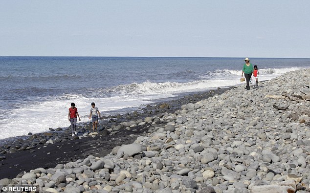 People walk on the beach where the piece of wreckage appeared on Wednesday on the north coast of La Reunion