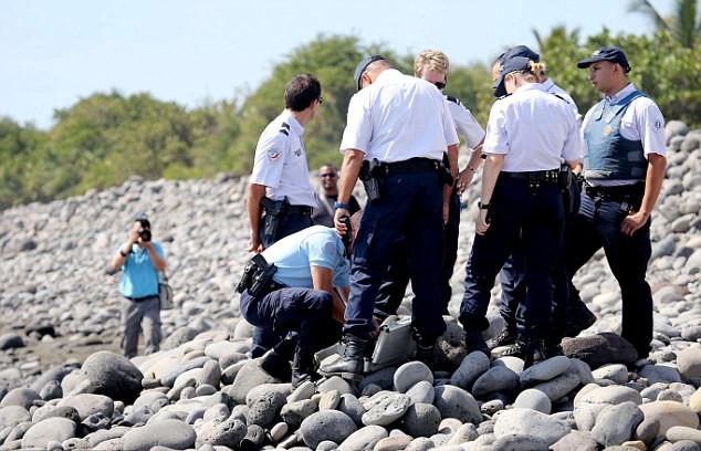 Các nhân viên cảnh sát kiểm tra mảnh vỡ được tìm thấy trên bờ biển đảo của Ấn Độ Dương