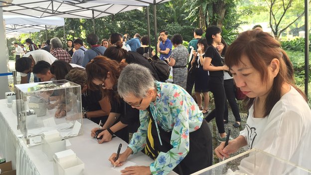 People sign a book of condolence at the Istana, Singapore, on 23 March 2015