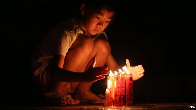 A girl lights candles to pray for victims of a capsized tourist ship in Jianli, Hubei province, China, 05 June 2015.