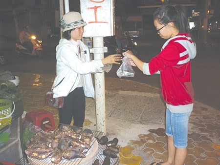 Huyền Trang (đội nón) đang bán khoai cho khách.