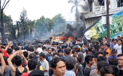 Residents gather next to the crash site of a military Hercules plane in Medan, North Sumatra province on June 30, 2015 (AFP Photo/Muhammad Zulfan Dalimunthe)