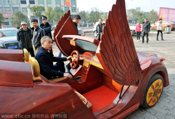 Yu poses in his homemade wooden sports car on a street.