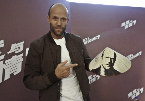 Jason Statham bất ngờ với chiếc nón lá có vẽ chân dung mình mà fan Việt dành tặng cho anh. Ảnh: Nick M.