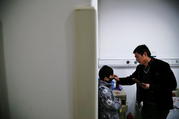 Chen Yuntao helps his son wear a mask at the hospitals ward so as to prevent infection, because a local citizen wants to see his son on Monday.