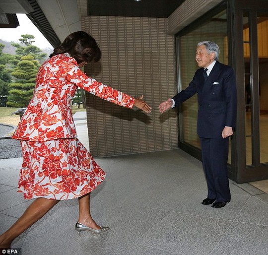 Im going in: Michelle Obama stumbles as she attempts an awkward combination of curtsey, western handshake and Japanese bow when meeting Emperor Akihito in Tokyo. Matters were not helped by the fact that she towers over him
