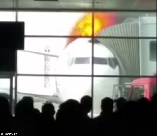 Terror at the terminal: Horrified airline passengers look on from the gate after the plane they were due to board bursts into flames at at an airport in Kazakhstan