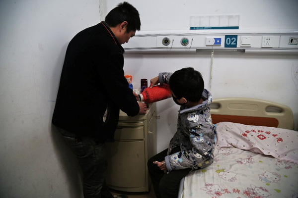 Chen Minghao helps his father serve tea for his visitors, who came to see them at the hospitals ward in Hefei, capital city of East Chinas Anhui province on Monday.