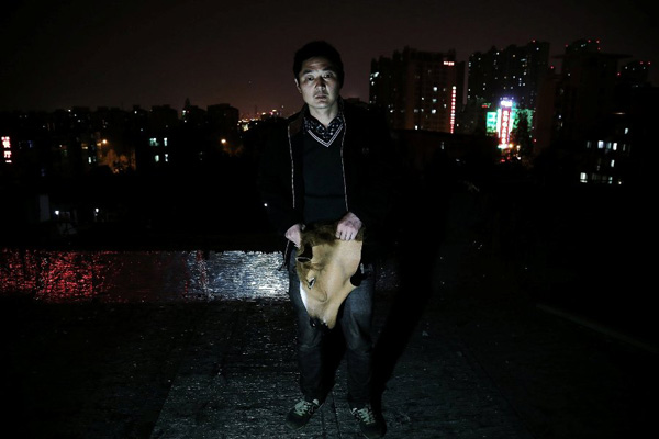Chen Yuntao takes a photo with his horse head mask late at night in Hefei, capital city of Anhui province on Monday. He doesnt know whether he will be begging for help on the road the next day.