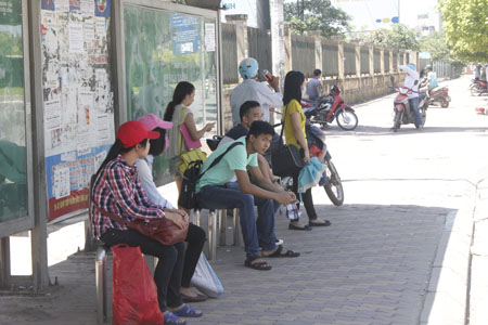 Thí sinh chờ xe bus bên ngoài bến xe trong thời tiết nắng nóng.