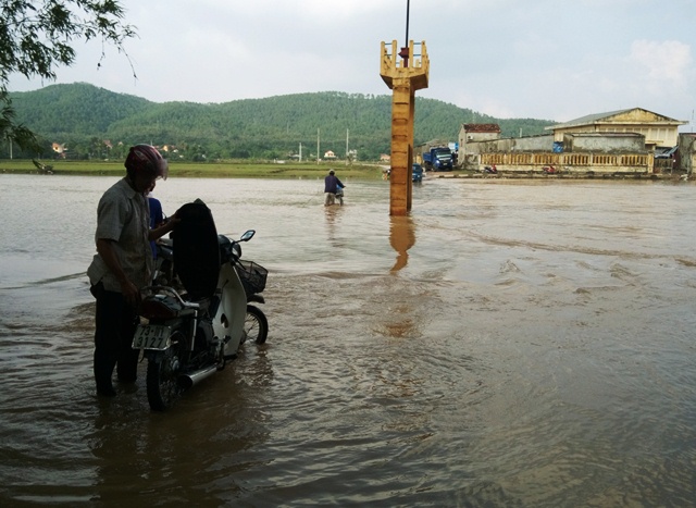 Một con đường đi vào xã Phù Hóa (Quảng Trạch, Quảng Bình) bị ngập trong nước, nhiều người dân dắt cả xe máy lội qua. Ảnh: M.K