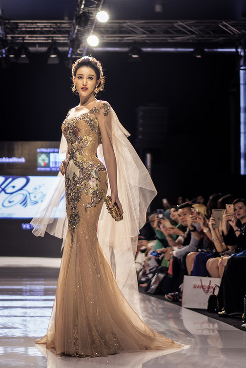 
Trước đó cô diện váy xuyên thấu khi làm vedette tại Malaysia Fashion Week. Điểm nhấn của chiếc váy nằm ở phần choàng vai cánh tiên, vừa đậm nét nữ tính vừa thể hiện vẻ mạnh mẽ.
