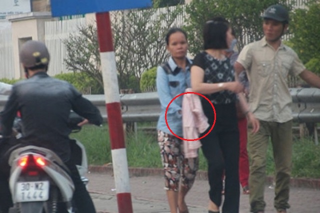
Người phụ nữ tiến tới móc điện thoại của một người dân trong sự hỗ trợ của đồng bọn. Ảnh cắt từ clip.

