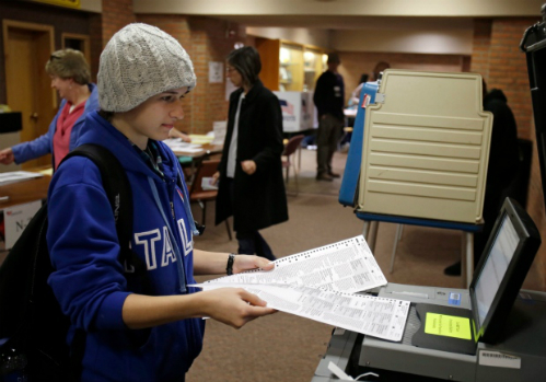 
Một cử tri Ohio cho lá phiếu của mình vào máy quét trong cuộc bầu cử tổng thống năm 2012. Ảnh: AP.
