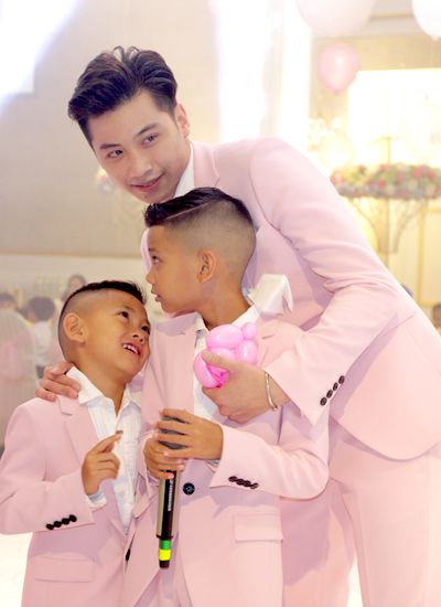 Con trai riêng của chồng Hà Kiều Anh tên Huỳnh Nhật Minh (sinh năm 1992) bên cạnh hai em Vương Khang (cầm micro) và Vương Khôi - hai con trai của hoa hậu và người chồng doanh nhân.