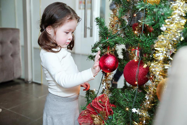 
Bé Cadie Mộc Trà thích thú khám phá quả cầu đỏ rực dùng để trang trí cây thông Noel.
