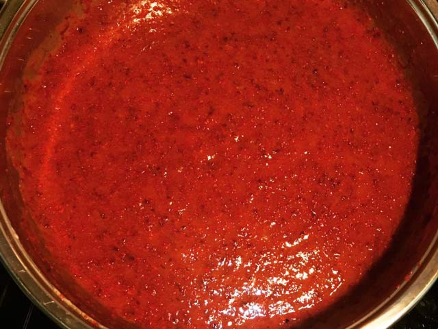Tiếp đến cho ớt bột HQ, ớt bột VN vào quấy đều trong khoảng 20p cho ớt nên màu đẹp rồi đổ tiếp hỗn hợp hành gừng tỏi xay nhuyễn, thêm nước mắm vào trộn đều.