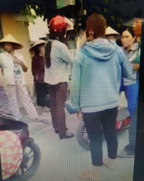 Người phụ nữ đội mũ bảo hiểm màu đỏ bị người dân nghi ngờ bắt cóc trẻ em. Ảnh chụp màn hình clip