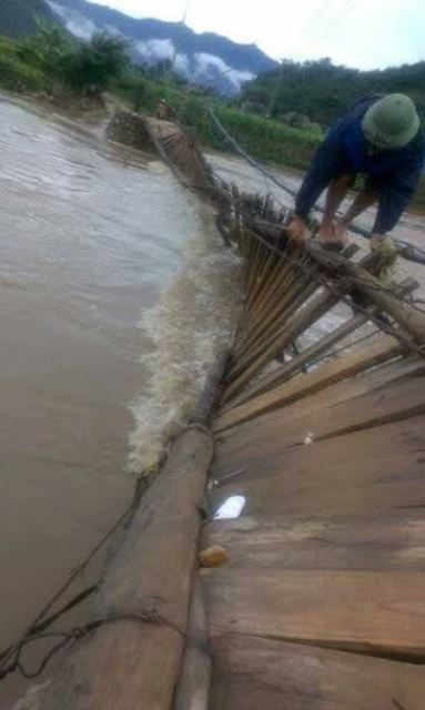 Người dân bản Nà Phát (xã Phúc Than, huyện Than Uyên, tỉnh Lai Châu) vượt qua cầu treo bị lật do lũ cuốn rất nguy hiểm.