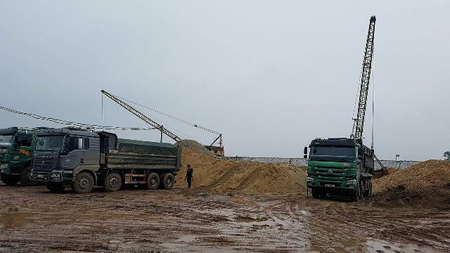Những xe tải trọng lớn chuẩn bị vận chuyển cát sỏi qua đê.