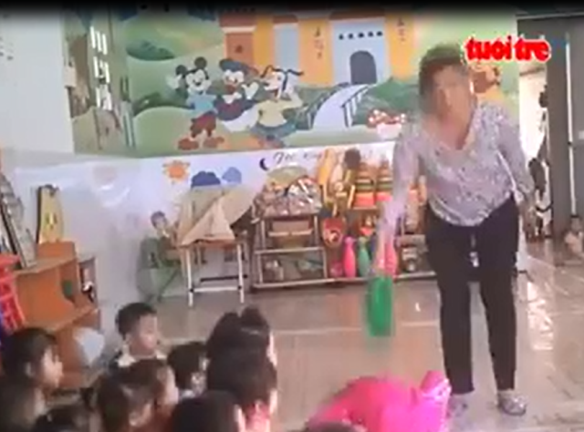 Bà Linh cầm can nhựa đánh thẳng đầu bé gái. Ảnh cắt từ clip của TuoitreTV