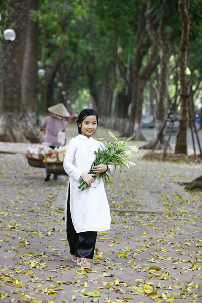 
Một mẫu nhí thoải mái tạo dáng trên vỉa hè rộng trải lá vàng.
