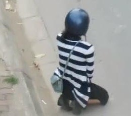 Hình ảnh cô gái quỳ gối giữa đường bị dân mạng lên án. Ảnh cắt từ clip.