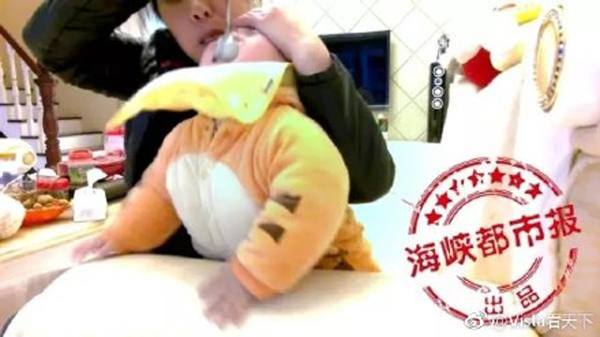 
Mặc cho đứa bé đang khóc lóc, Zhou vẫn ngửa cổ bé ra để bón bột. Ảnh: Shanghai Daily
