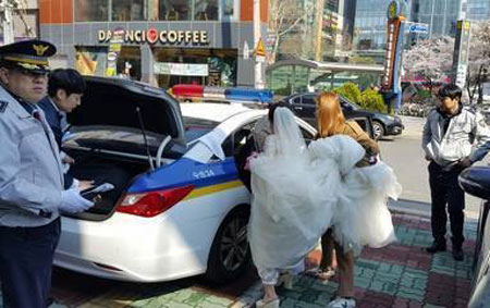 
Cô dâu, chú rể được cảnh sát cho đi nhờ xe tới nơi tổ chức hôn lễ. Ảnh: Allkpop.
