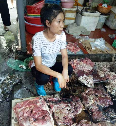 Chị Xuyến cùng khoảng 50kg thịt lợn bị hắt dầu luyn trộn với chất thải. Ảnh cắt từ video.