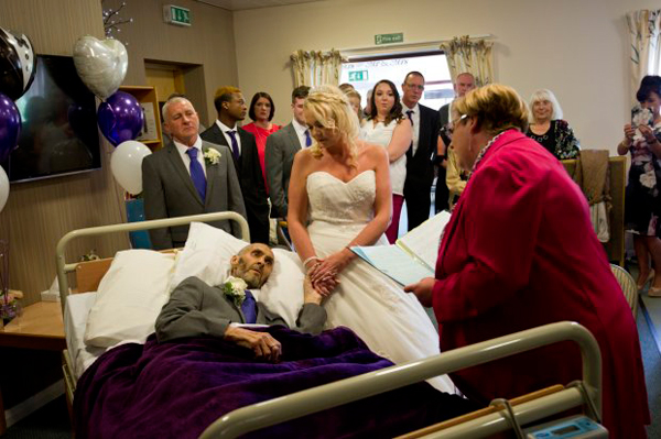 
Chú rể nằm trên giường bệnh, nắm tay cô dâu và trao lời nguyện ước. Ảnh: Manchester Evening News.

