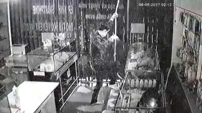 Tên trộm đu dây xuống cửa hàng điện thoại. Ảnh: Cắt từ clip.