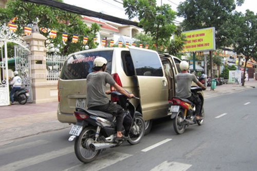 
Hai người đi xe máy đẩy chiếc ô tô 7 chỗ chết máy trên đường phố Sài Gòn.
