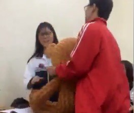 
Ch&agrave;ng trai &ocirc;m theo ch&uacute; gấu để tỏ t&igrave;nh với bạn g&aacute;i. Ảnh cắt từ clip. 
