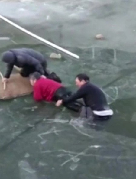 Một người đ&agrave;n &ocirc;ng kh&aacute;c hỗ trợ &ocirc;ng Lei đưa cụ b&agrave; l&ecirc;n bờ. Ảnh: Reuters