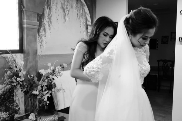 
Cô dâu Helen Nguyễn được ca sĩ Lam Anh chỉnh sửa lại váy cưới trước giờ bước vào lễ đường.
