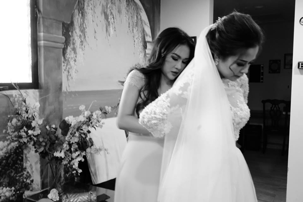 Cô dâu Helen Nguyễn được ca sĩ Lam Anh chỉnh sửa lại váy cưới trước giờ bước vào lễ đường.