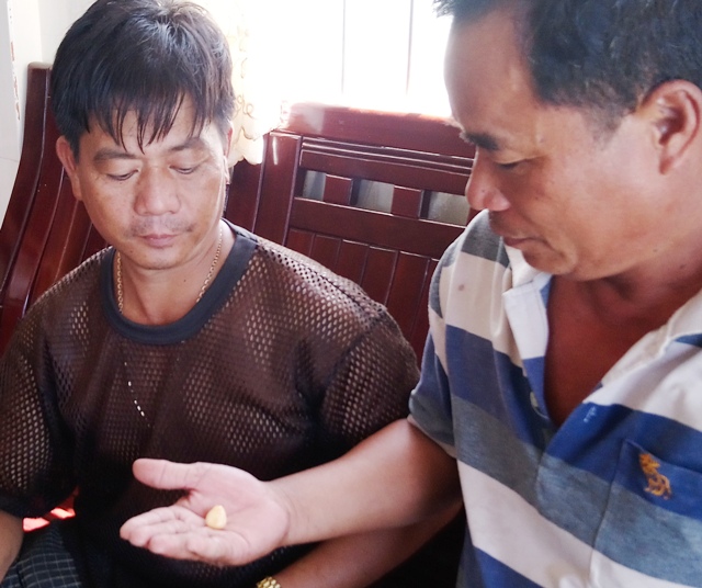 Anh Nam (tr&aacute;i) đang cho kh&aacute;ch xem vật lạ được cho l&agrave; ngọc ốc qu&yacute; hiếm. (Ảnh: CTV)