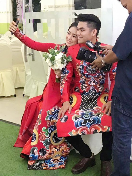 Trong ngày lên xe hoa, nữ diễn viên diện áo dài đỏ thêu họa tiết cầu kỳ của NTK Minh Châu, ton sur ton với ông xã Trung Kiên.