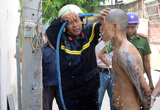 Trung tá Đinh Ngọc Đại, Đội trưởng Đội cứu nạn cứu hộ, dùng nước rửa vôi trên cơ thể nam thanh niên. Ảnh: Mai Vinh.