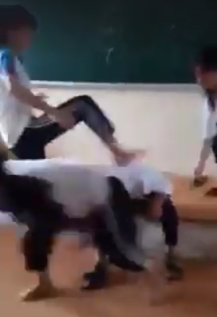 Nữ sinh bị nhóm bạn ngồi lên đầu, đạp vào người trước khi bị lột áo. Ảnh cắt từ clip.